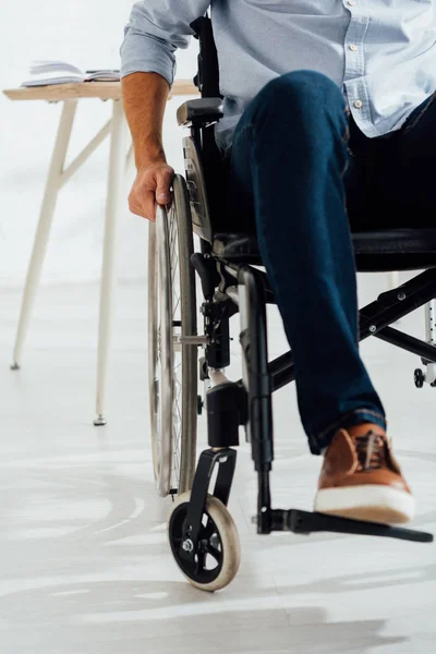 Cropped view of man holding hand on wheelchair wheel — Stock Photo