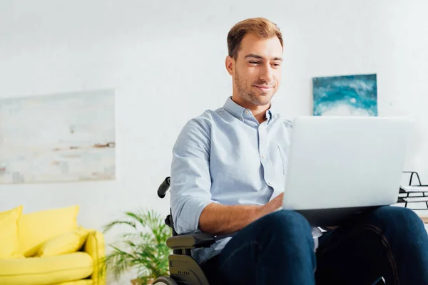 Smiling freelancer in wheelchair using laptop in living room — Stock Photo