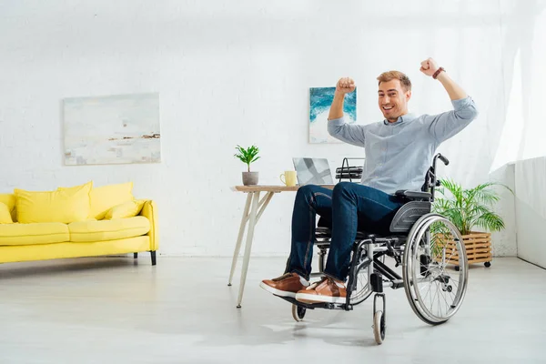 Веселый мужчина в инвалидной коляске смотрит в камеру в гостиной — стоковое фото