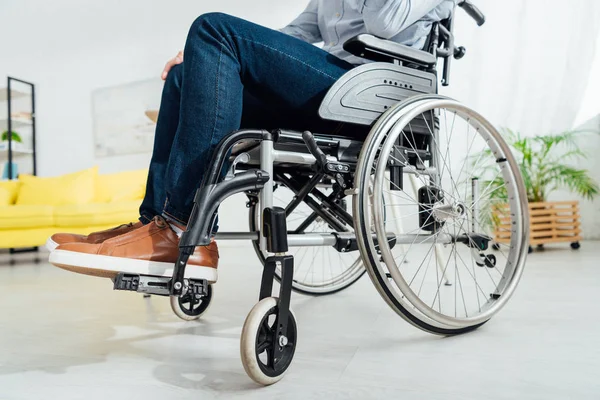 Vue du bas de l'homme assis en fauteuil roulant dans le salon — Photo de stock