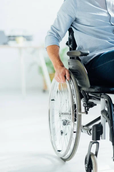 Vista parcial del hombre sentado en silla de ruedas en el salón - foto de stock