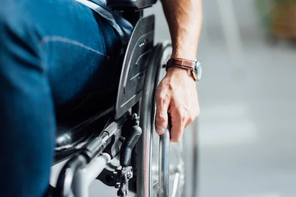 Vista ritagliata dell'uomo che tiene la mano sulla sedia a rotelle — Foto stock