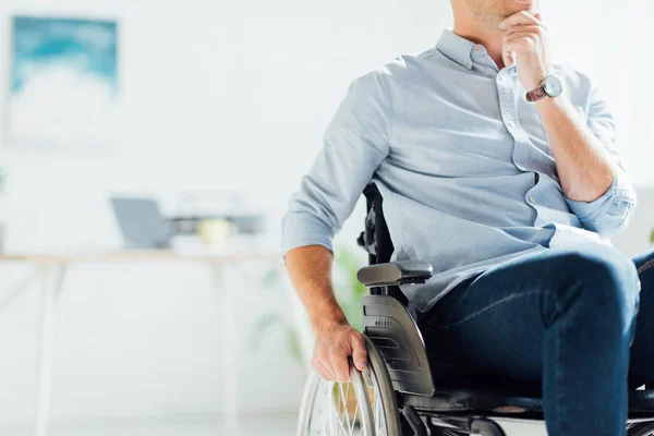 Cropped view of pensive man in wheelchair with hand on chin — Stock Photo