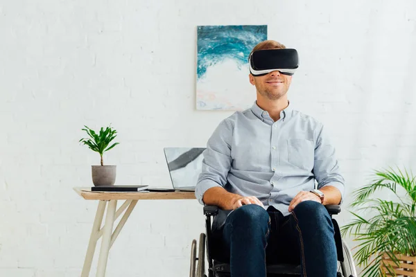 Smiling disabled man in wheelchair using virtual reality headset in living room — Stock Photo