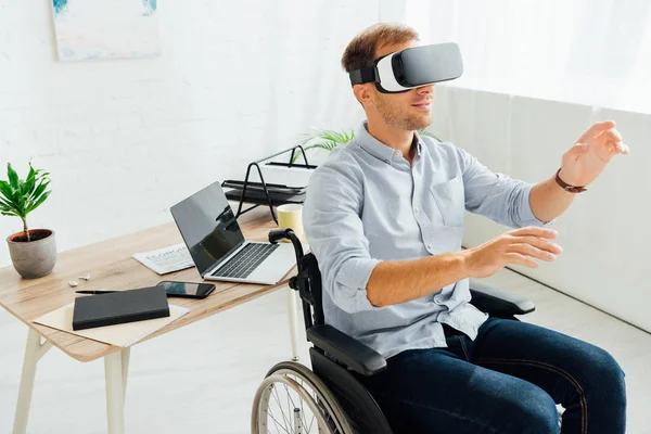 Hombre en silla de ruedas usando auriculares vr por lugar de trabajo - foto de stock