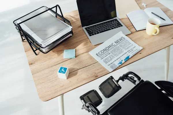 Cube with disabled sign and wheelchair by workplace — Stock Photo
