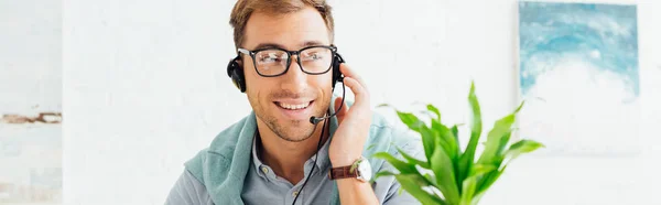 Smiling call center operator talking on headset, panoramic shot — Stock Photo
