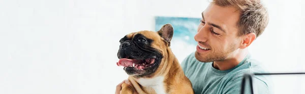 Plan panoramique d'un homme souriant tenant un bouledogue français — Photo de stock