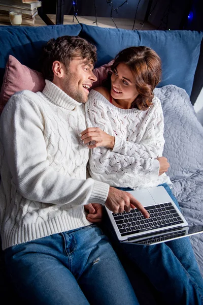 Vue grand angle de petite amie souriante et beau petit ami pointant avec le doigt à l'ordinateur portable — Photo de stock