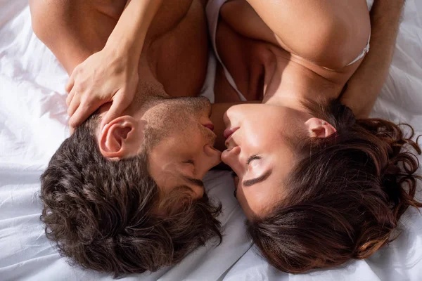 Вид сверху на подругу и бойфренда, целующихся и обнимающихся в постели — стоковое фото