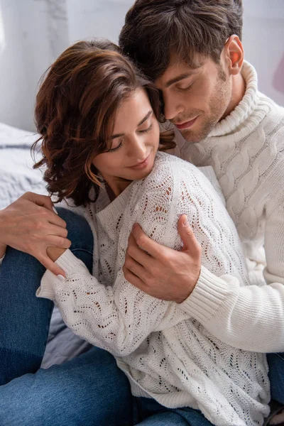 Handsome boyfriend hugging girlfriend in sweater with closed eyes — Stock Photo