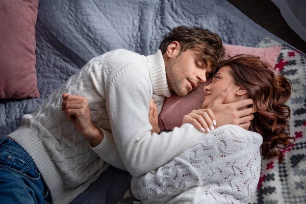 Хлопець і дівчина в светрах обіймаються і лежать в ліжку — стокове фото