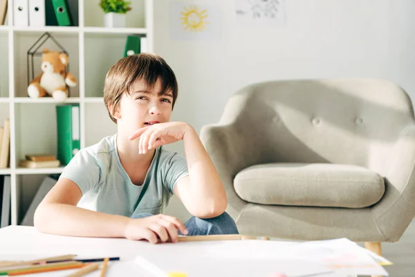 Nachdenkliches Kind mit Legasthenie sitzt am Tisch und schaut weg — Stockfoto