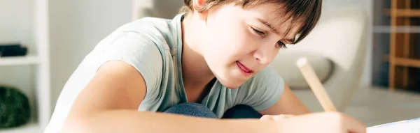 Panoramic shot of kid with dyslexia drawing with pencil — Stock Photo