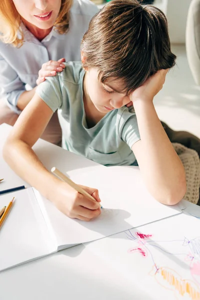Обрізаний вид дитячого психолога і сумного хлопчика з дислексією малюнок олівцем — стокове фото