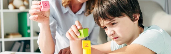 Plan panoramique de l'enfant avec dyslexie et psychologue de l'enfant jouant avec les blocs de construction — Photo de stock