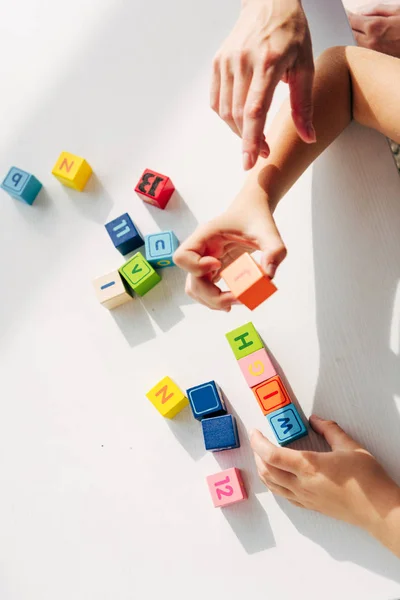 Vista recortada del psicólogo infantil y el niño con dislexia jugando con bloques de construcción - foto de stock