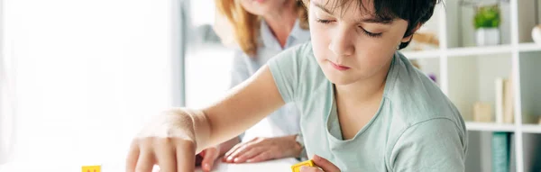 Plano panorámico de niño con dislexia sentado en la mesa - foto de stock