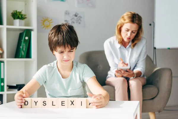 Foco seletivo de criança com dislexia segurando cubos com dislexia lettering — Fotografia de Stock