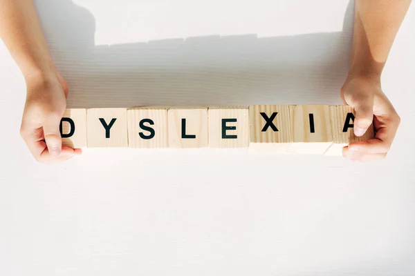 Cropped view of kid with dyslexia holding wooden cubes with lettering — Stock Photo