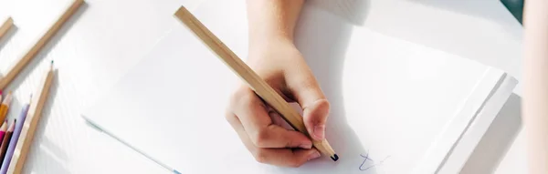 Cropped view of kid with dyslexia drawing on paper with pencil — Stock Photo