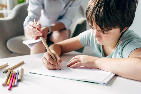 Selective focus of kid with dyslexia drawing on paper with pencil — Stock Photo