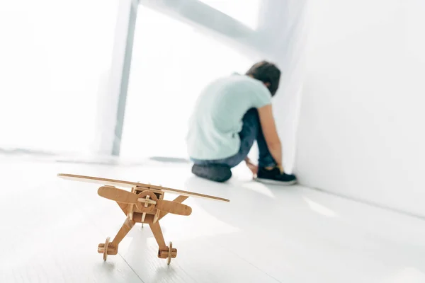 Selective focus of wooden plane and sad kid with dyslexia sitting on background — Stock Photo