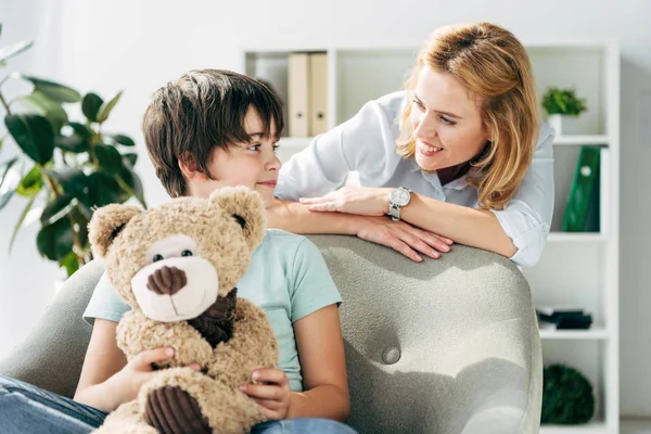 Kid with dyslexia holding teddy bear and child psychologist talking with him — Stock Photo