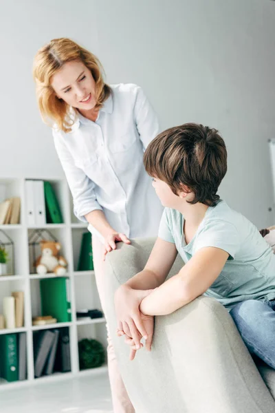 Kind mit Legasthenie sitzt auf Sessel und spricht mit Kinderpsychologe — Stockfoto