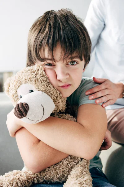 Kid with dyslexia holding teddy bear and child psychologist hugging him — Stock Photo