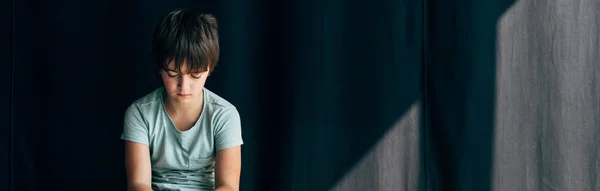 Panoramic shot of sad kid with dyslexia on black background — Stock Photo