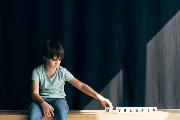 Bambino con dislessia che gioca con cubi di legno con scritte — Foto stock