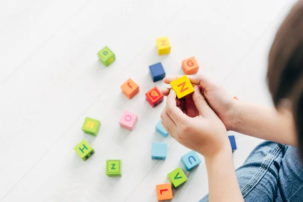 Visão cortada de criança com dislexia brincando com blocos de construção coloridos — Fotografia de Stock