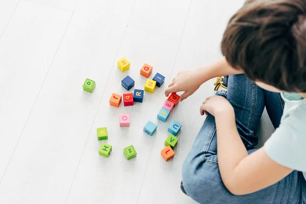 Visão cortada de criança com dislexia brincando com blocos de construção coloridos — Fotografia de Stock