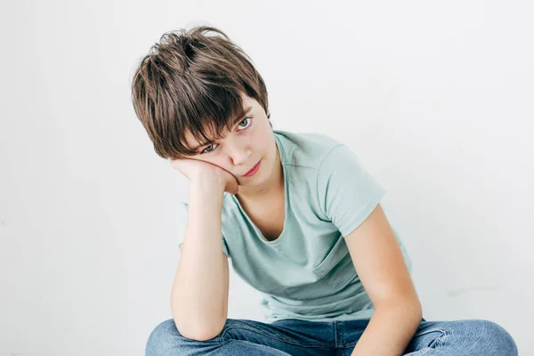 Niño triste con dislexia en camiseta mirando a la cámara aislada en blanco - foto de stock