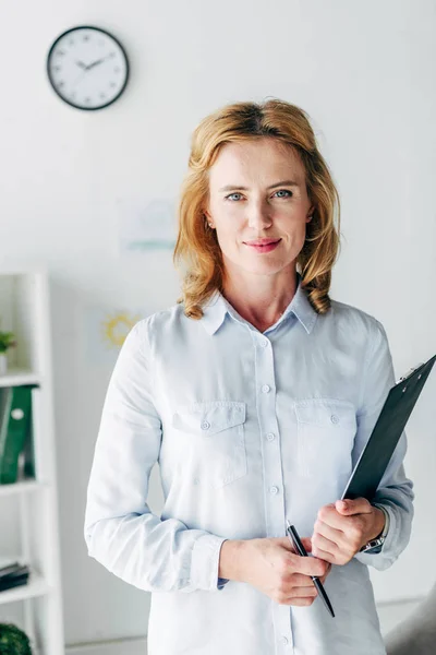 Attractive child psychologist in shirt looking at camera and holding folder — Stock Photo