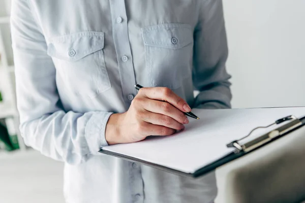 Vue recadrée d'enfant psychologue en chemise écriture sur presse-papiers — Photo de stock