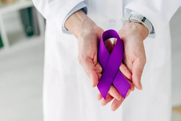 Vue recadrée du médecin tenant un ruban violet en clinique — Photo de stock