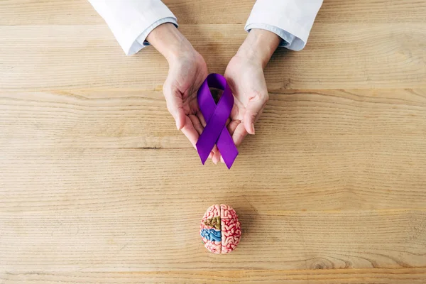 Cropped view of doctor holding purple ribbon in clinic — Stock Photo