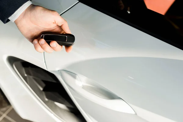 KYIV, UKRAINE - OCTOBER 7, 2019: cropped view of man holding car key near modern white porshe — Stock Photo