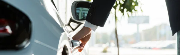 KYIV, UKRAINE - 7 OCTOBRE 2019 : prise de vue panoramique de l'homme ouvrant la porte du porshe dans la salle d'exposition de la voiture — Photo de stock