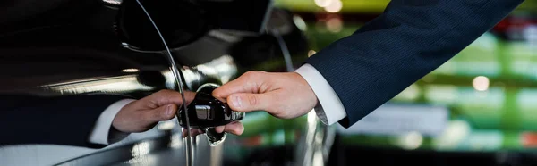 KYIV, UKRAINE - 7 OCTOBRE 2019 : prise de vue panoramique de l'homme ouvrant la porte de la voiture du porche noir — Photo de stock