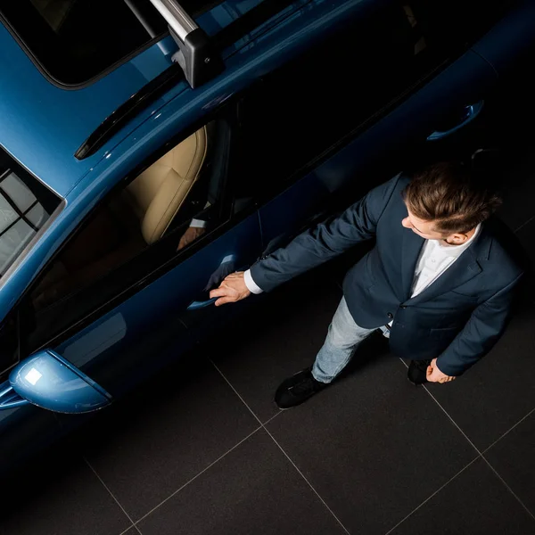 KYIV, UKRAINE - OCTOBER 7, 2019: top view of businessman in suit standing near blue porshe while opening car door — Stock Photo