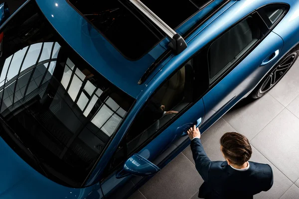 KYIV, UCRANIA - 7 DE OCTUBRE DE 2019: vista superior del hombre de negocios en traje de pie cerca de porshe al abrir la puerta del coche - foto de stock