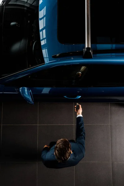 KYIV, UKRAINE - OCTOBER 7, 2019: top view of man in suit standing near blue porshe while opening car door — Stock Photo