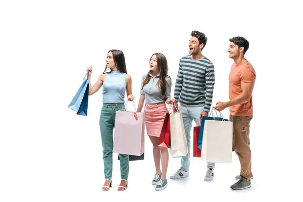 Amigos sorprendidos caminando con bolsas de compras juntos, aislados en blanco - foto de stock