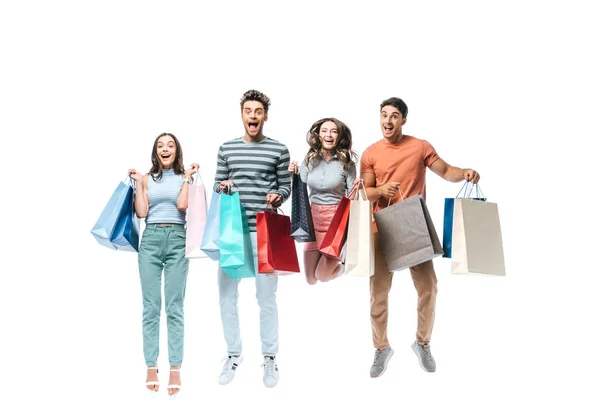 Amigos emocionados saltando y sosteniendo bolsas de compras, aislados en blanco - foto de stock