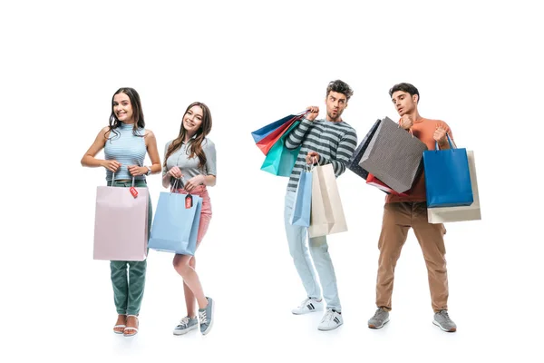 Beaux jeunes amis tenant des sacs à provisions avec des signes de vente, isolé sur blanc — Photo de stock