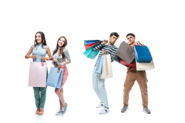 Amigos alegres sosteniendo bolsas de compras con carteles de venta, aislados en blanco - foto de stock