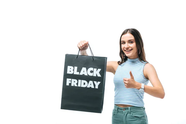 Mujer sonriente mostrando el pulgar hacia arriba y sosteniendo el bolso de la compra el viernes negro, aislado en blanco - foto de stock